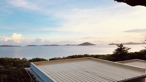 A building with a flat roof overlooking a body of water and distant landforms. - Cozy Room at Mamima BnB (Caramoan)
