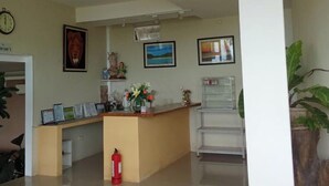 A reception area with a wooden counter, framed certificates, a clock, and a fire extinguisher. - Cozy Room at Mamima BnB (Caramoan)