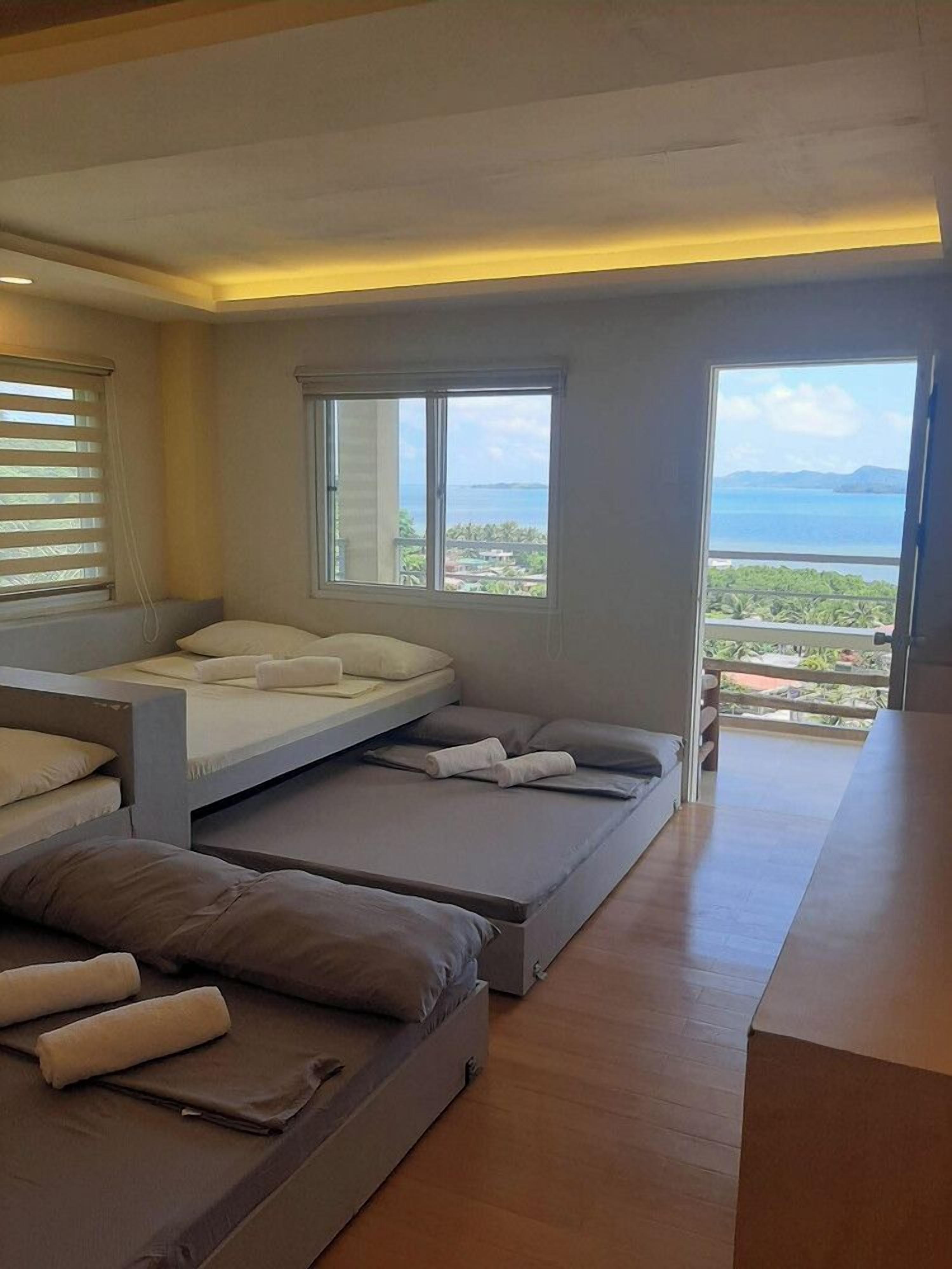 A modern bedroom with a bed, a sofa, and a view of the sea.