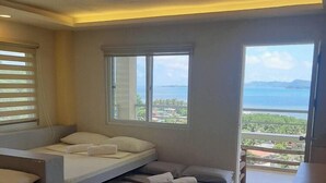 A modern bedroom with a bed, a sofa, and a view of the sea. - Cozy Room at Mamima BnB (Caramoan)