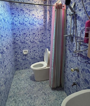 Un baño con pared de mosaicos, un inodoro, zona de ducha y un lavabo.