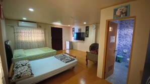Een kamer met twee bedden, een televisie, een stoel en een kleine badkamer.