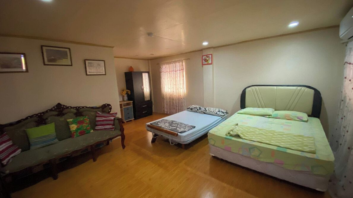 Una habitación con sofá, cama, armario y ventana con cortinas.