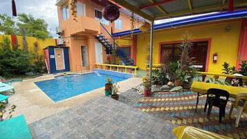 A swimming pool area with a staircase leading to a building, surrounded by potted plants and outdoor seating.
