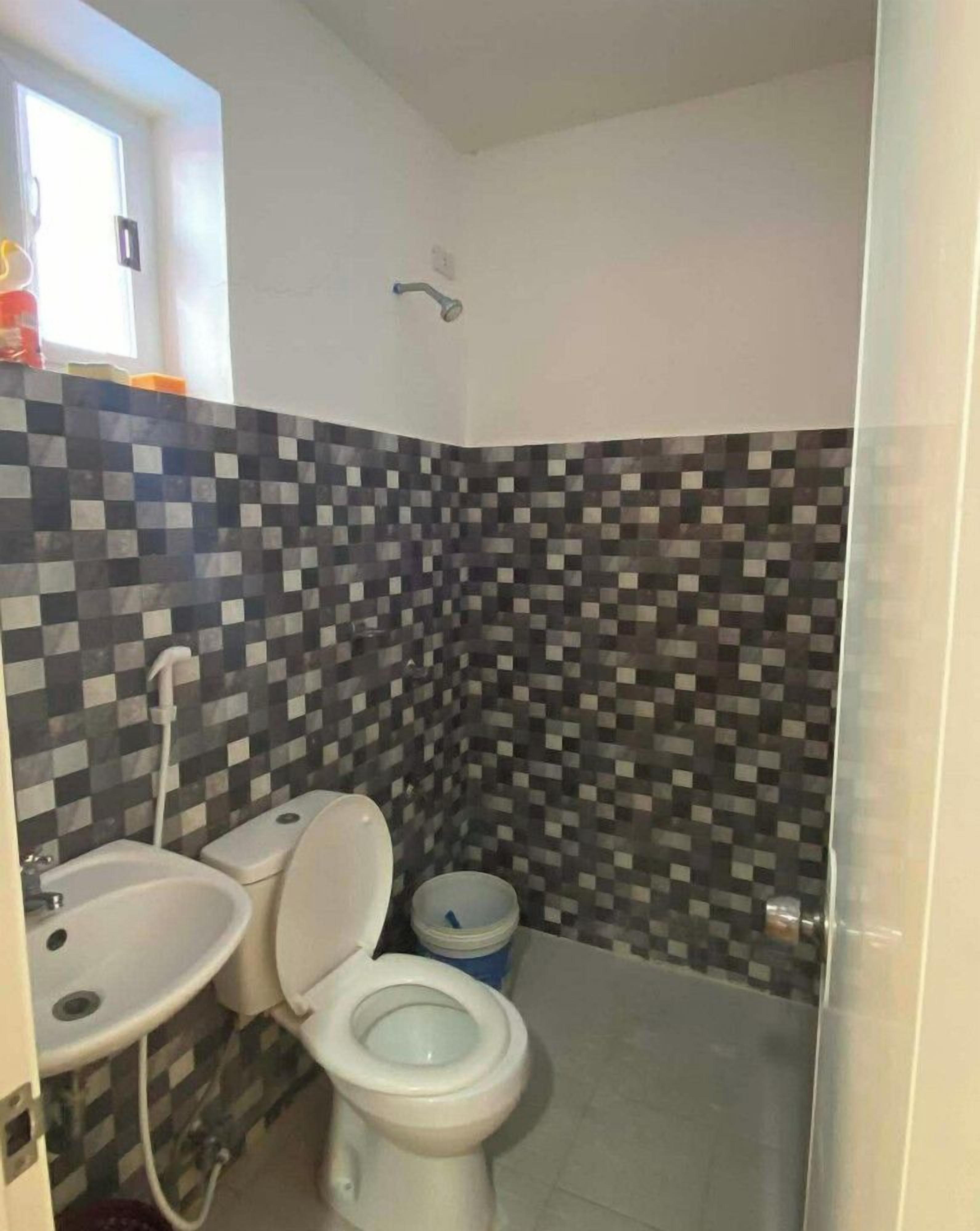 Kylpyhuone, jossa on laatoitettu seinä, wc-istuin, pesuallas ja suihku.
