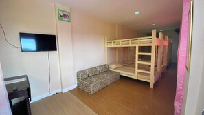 A room with bunk beds, a television, and a sofa.
