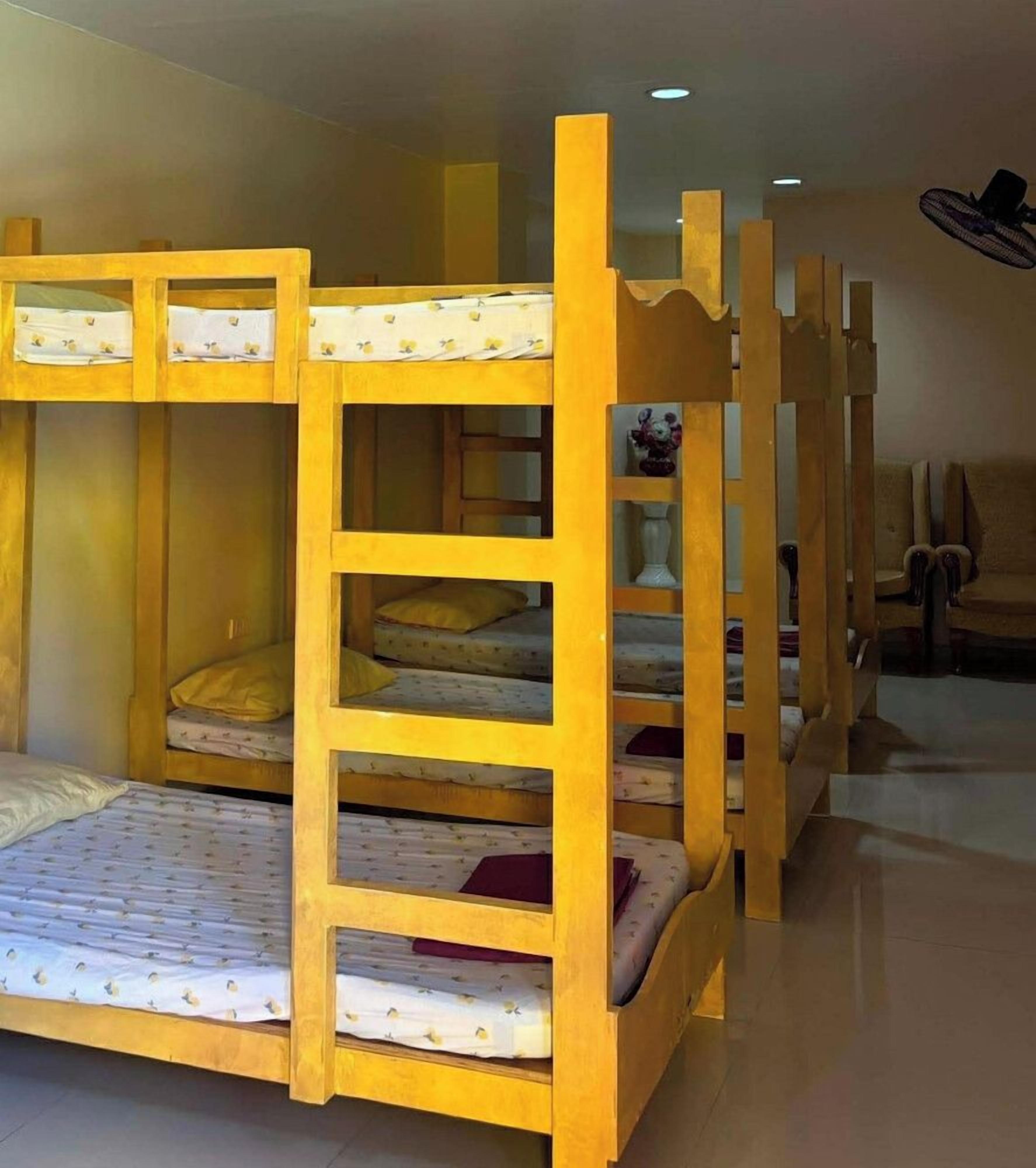 Una cama litera con escalera, una mesita pequeña y una silla en una habitación con piso de baldosas.