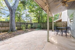 A covered patio with stone flooring, a table with chairs, and a ceiling fan. - King Bed 3B Townhome 2.7 miles from the stadium. (Auburn)