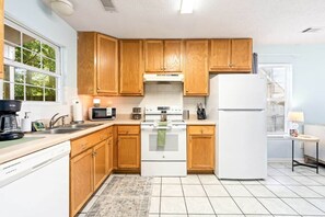 A kitchen with wooden cabinets, a white stove, a microwave, and a refrigerator. - King Bed 3B Townhome 2.7 miles from the stadium. (Auburn)