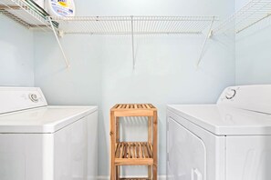 A laundry room with two white washing machines, a wooden shelf, and a hanging drying rack. - King Bed 3B Townhome 2.7 miles from the stadium. (Auburn)
