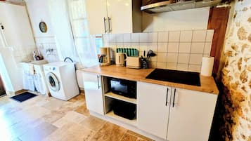 Cozinha compacta com máquina de lavar, torradeira e fogão.
