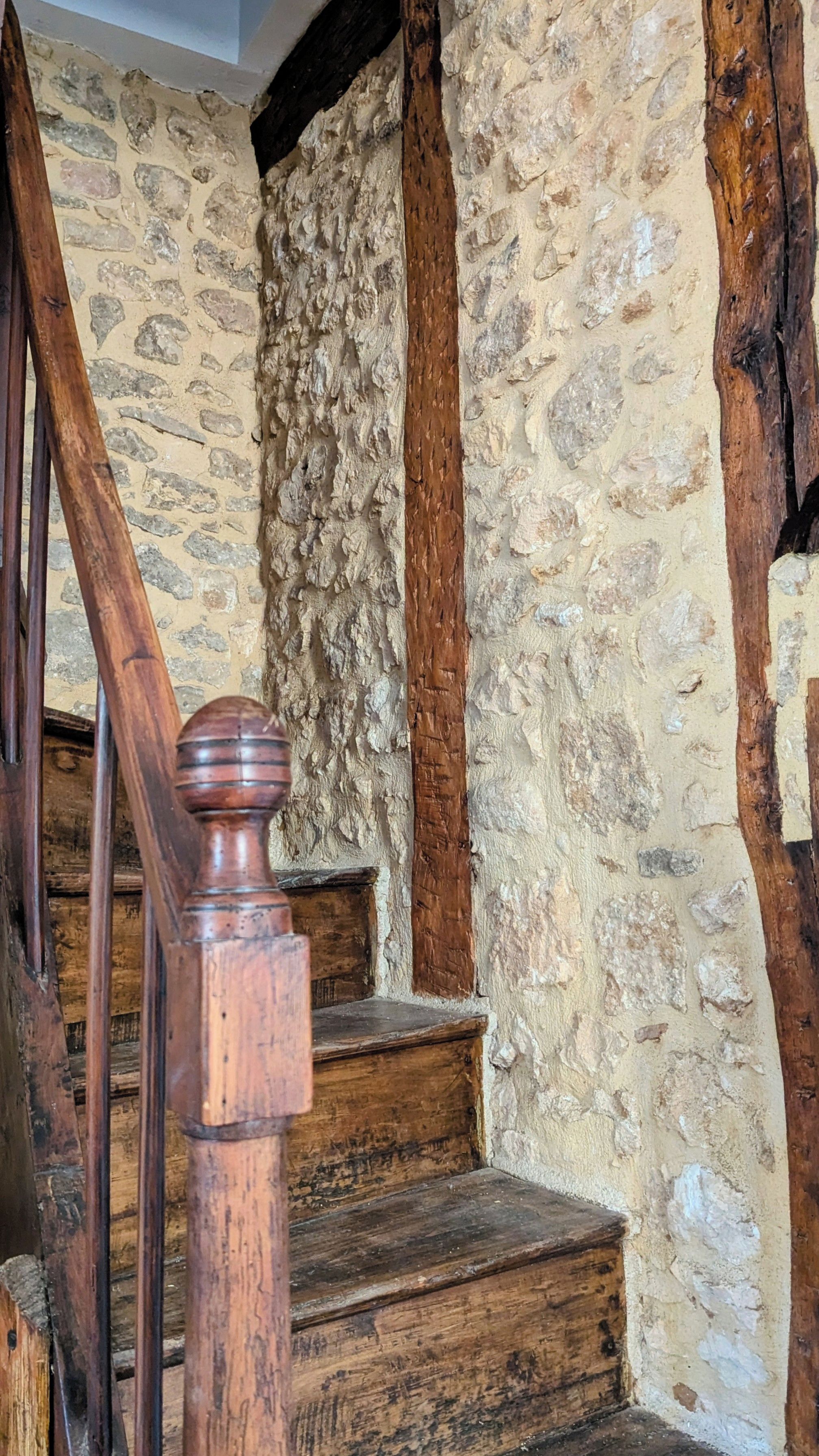 Un escalier en bois avec un mur de pierres en arrière-plan.