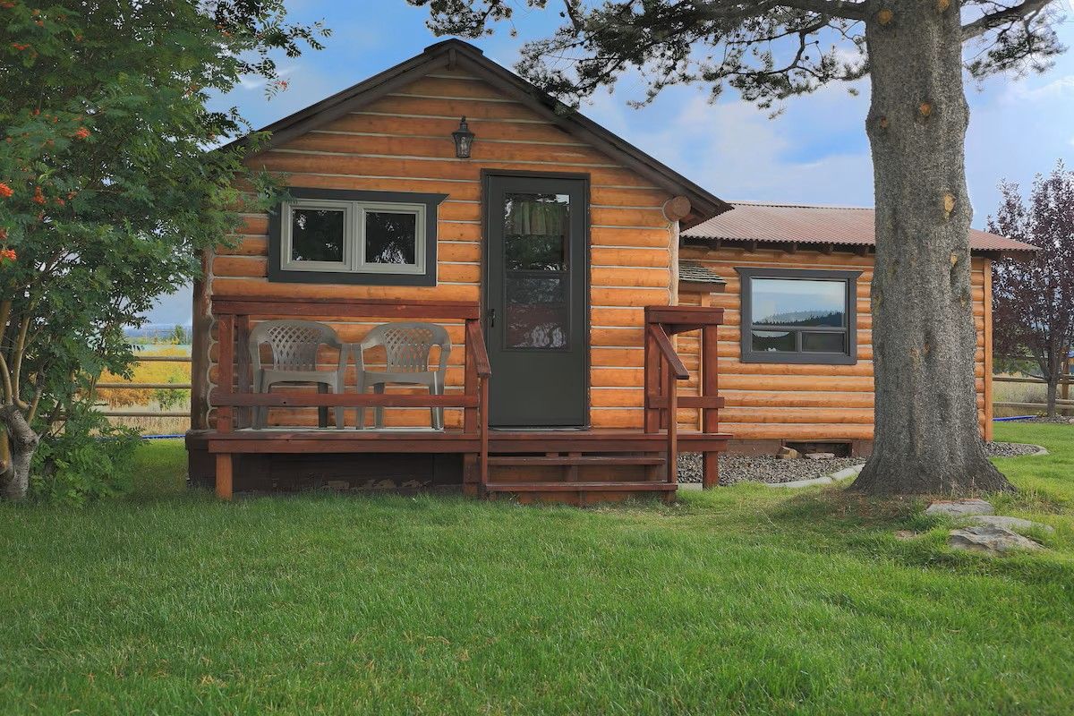 A wooden cabin with a porch, a door, and a window.