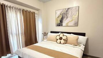 A bedroom with a bed, curtains, a painting, and a nightstand.