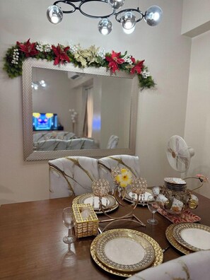 A dining area with a large mirror, a chandelier, and festive decorations. - Kuya Awen’s Staycation 12H (Parañaque)