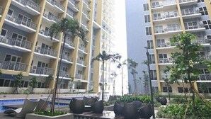 A high-rise residential building with multiple balconies, a swimming pool, and outdoor seating areas. - Kuya Awen’s Staycation 12H (Parañaque)