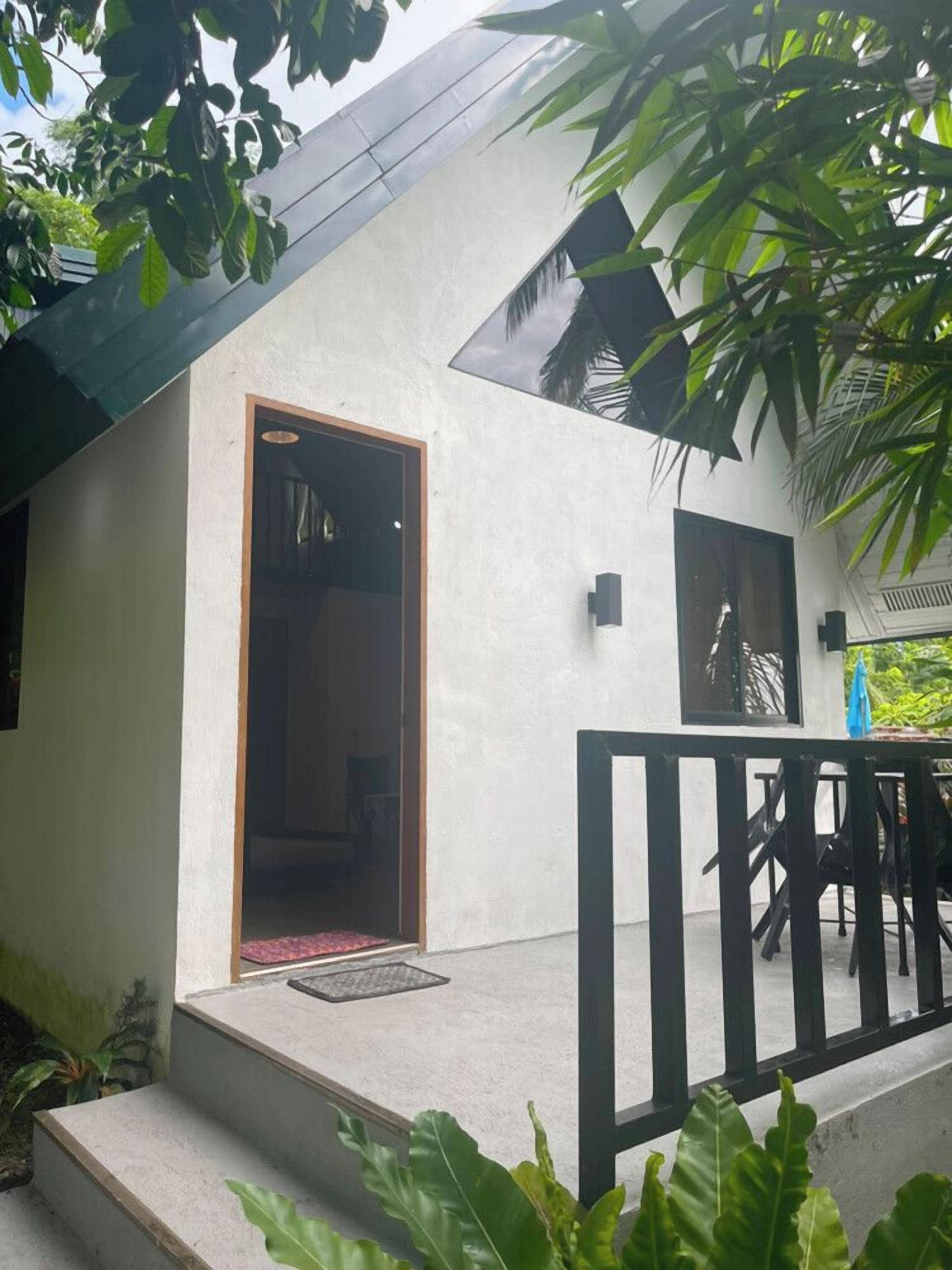 A building with a white exterior, a wooden door, and a black railing.