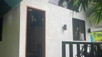 A building with a white exterior, a wooden door, and a black railing.