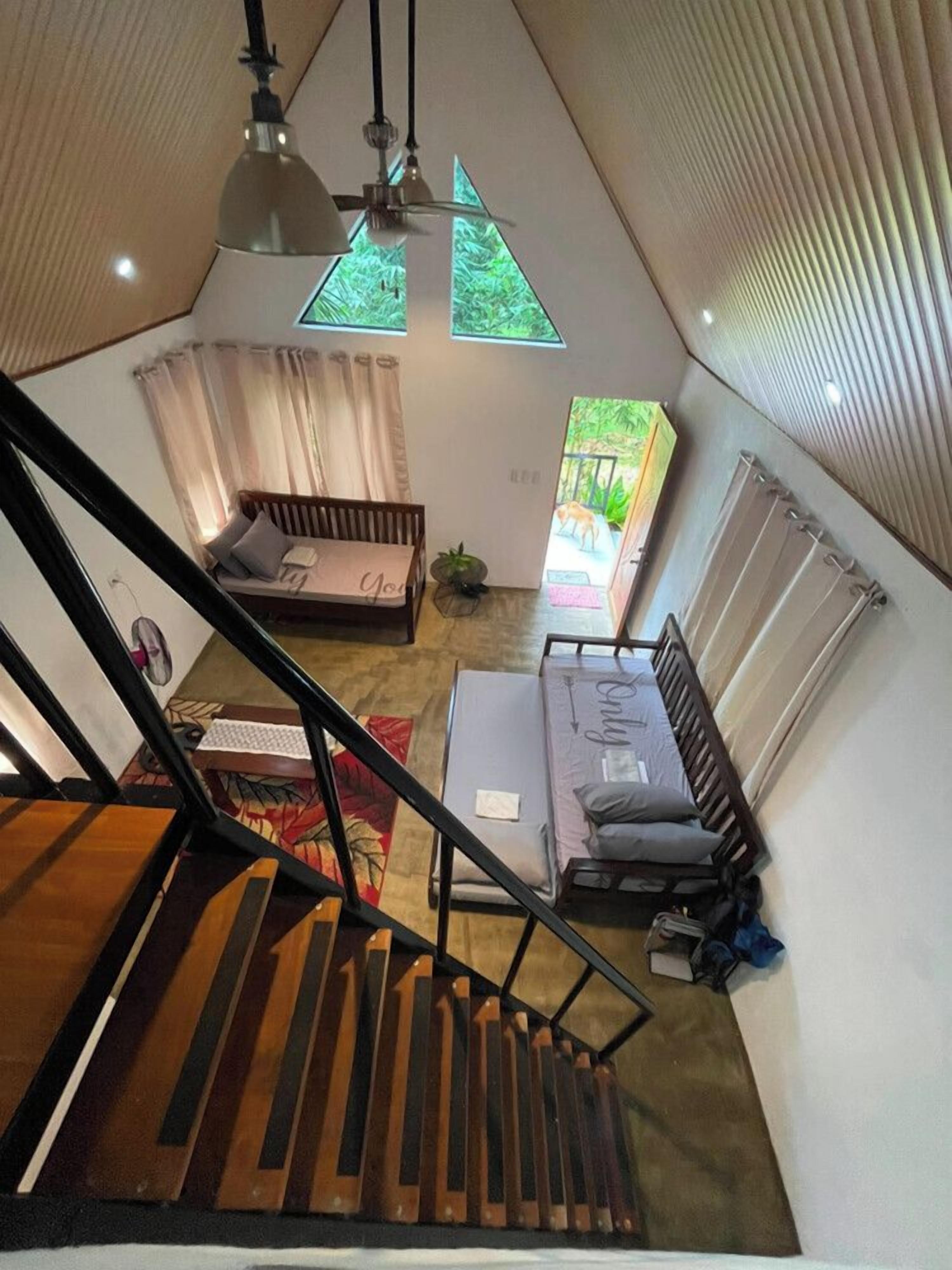 Habitación estilo loft con escalera, cama, escritorio y vistas a un jardín.