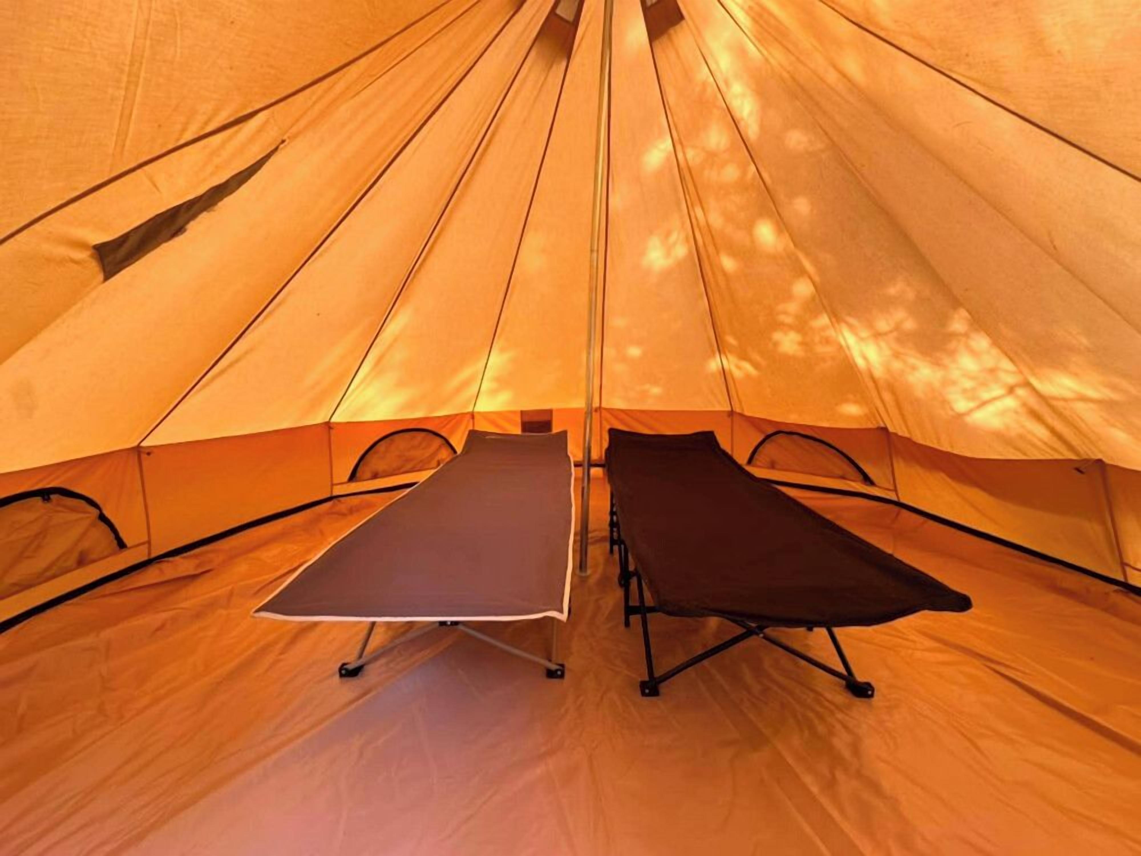Une tente équipée de deux lits pliants et d’une table.