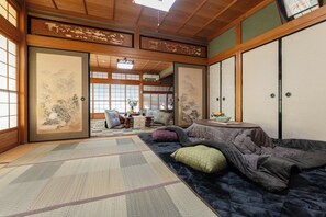 A traditional Japanese room with tatami flooring, sliding doors, and a view of a garden.