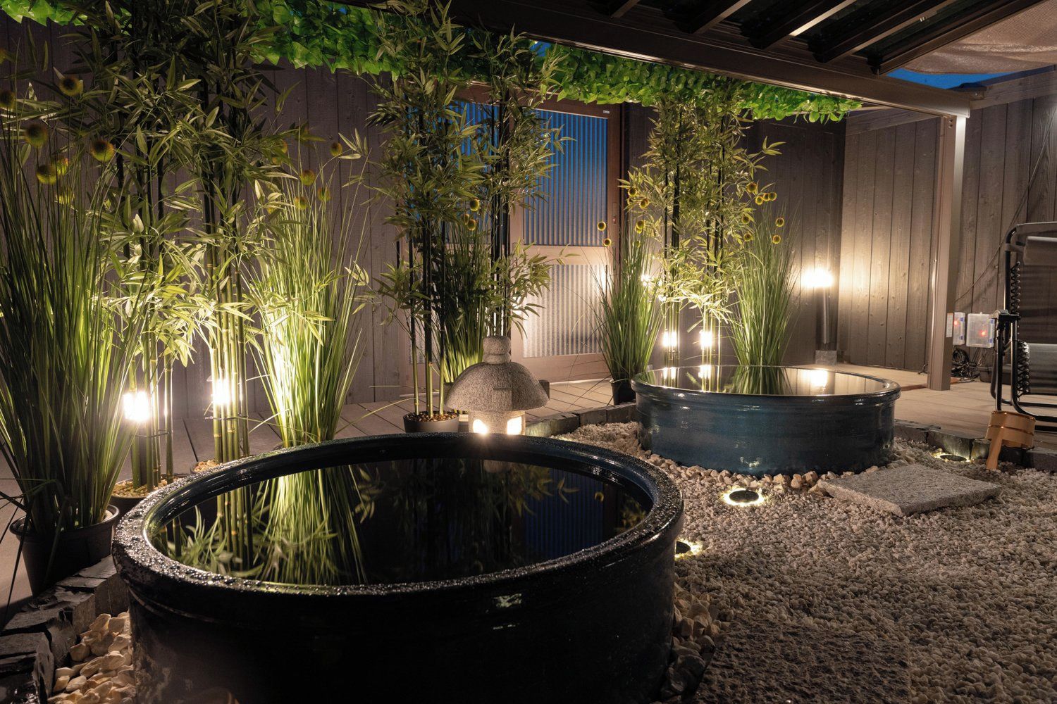A garden area with bamboo plants, a water feature, and a wooden fence.