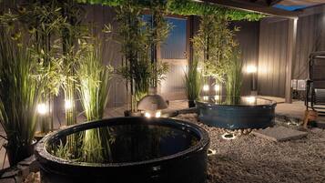 A garden area with bamboo plants, a water feature, and a wooden fence.