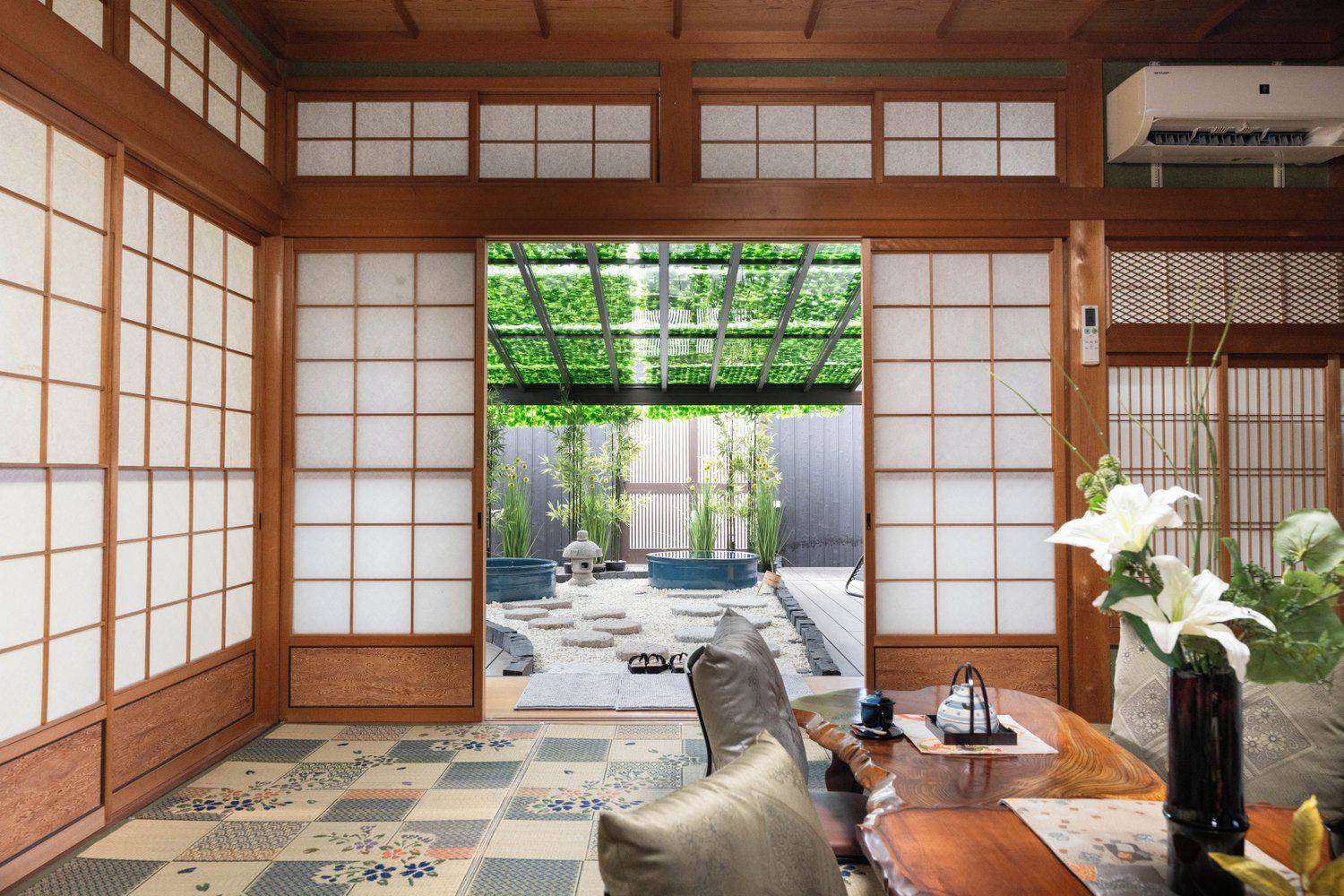 A traditional Japanese room with tatami flooring, a shoji screen door, and a view of an outdoor garden.