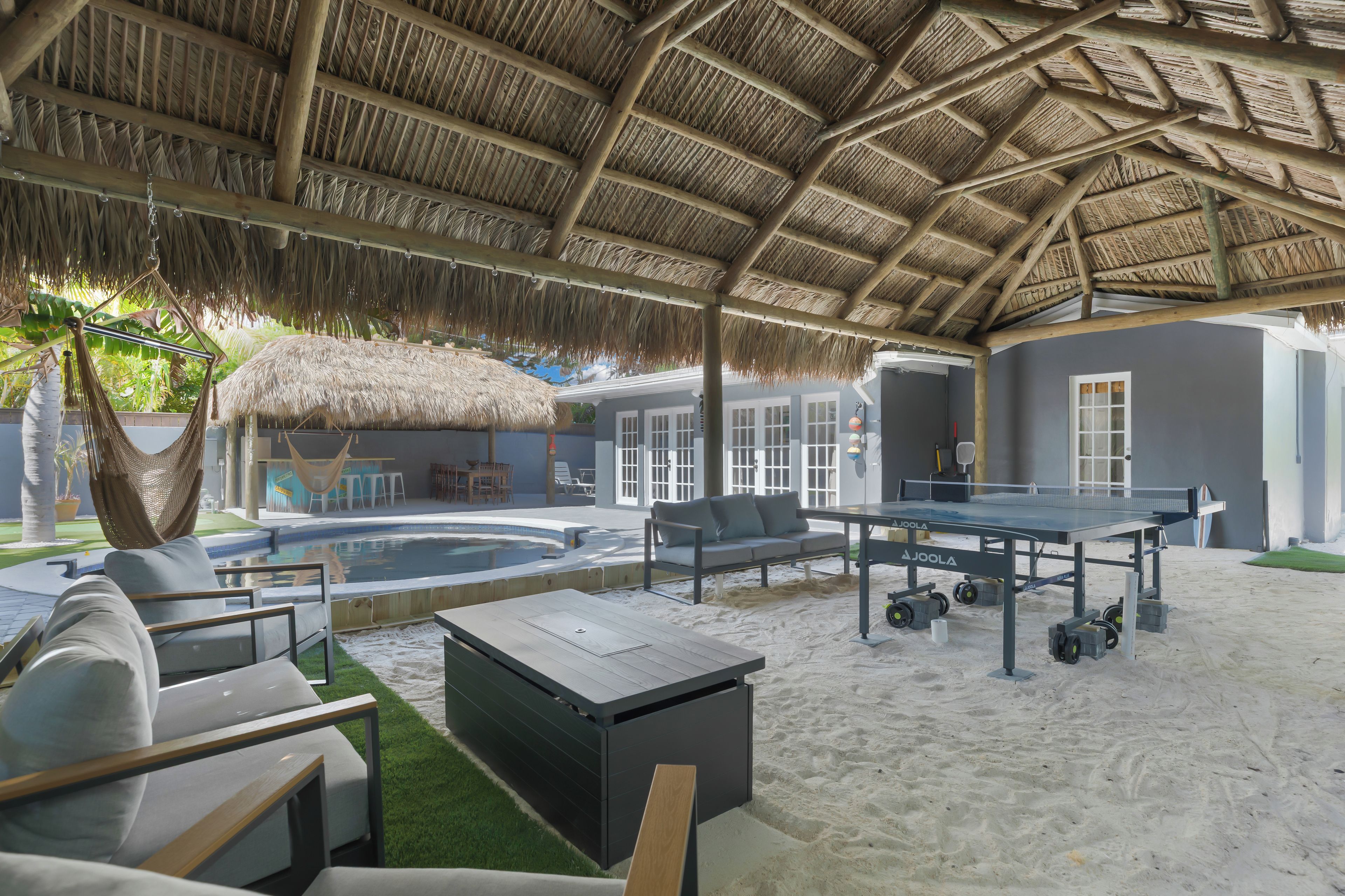 Un espace extérieur abrité comprenant une piscine, des chaises longues, une table de ping-pong et un hamac.