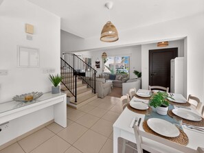 A modern kitchen with a dining area, a staircase, and a view of the outdoors. - Villa Andreas: Private Pool & Modern Comfort (Protaras)