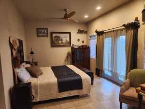 A bedroom with a bed, a ceiling fan, a dresser, a chair, and a window with curtains. - Sweet Somers one bedroom+home with outstanding views above Flathead Lake. (Somers)