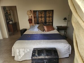 A bedroom with a bed, a headboard, a nightstand, a lamp, a suitcase, and a mirror. - Sweet Somers one bedroom+home with outstanding views above Flathead Lake. (Somers)