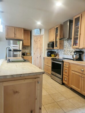 A kitchen with wooden cabinets, a stainless steel refrigerator, a microwave, an oven, and a sink. - Sweet Somers one bedroom+home with outstanding views above Flathead Lake. (Somers)