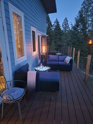 A deck with a sofa, a chair, and a table with a glass top. - Sweet Somers one bedroom+home with outstanding views above Flathead Lake. (Somers)