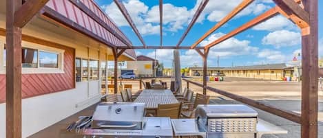 An outdoor patio with a barbecue grill, a table, and chairs.