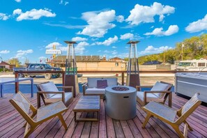 An outdoor deck with seating, a fire pit, and a view of a restaurant in the background. - 12 Highlander (Williams)