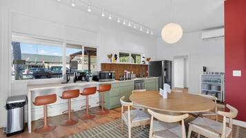 A modern kitchen with bar stools, a dining table, and a view of the outside.