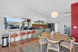 Una cocina moderna con taburetes de bar, una mesa de comedor y vistas al exterior.