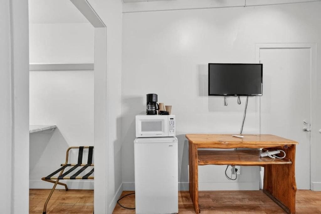 Una pequeña cocina americana con microondas, cafetera y una mesa.