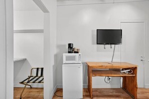 Una pequeña cocina americana con microondas, cafetera y una mesa.
