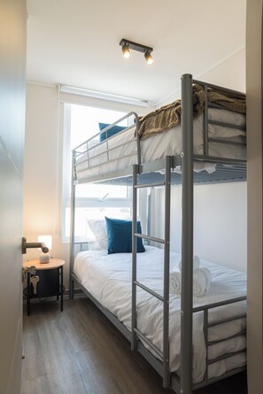 Ein Schlafzimmer mit Etagenbetten, einem Fenster, einem Schreibtisch und einer Lampe.