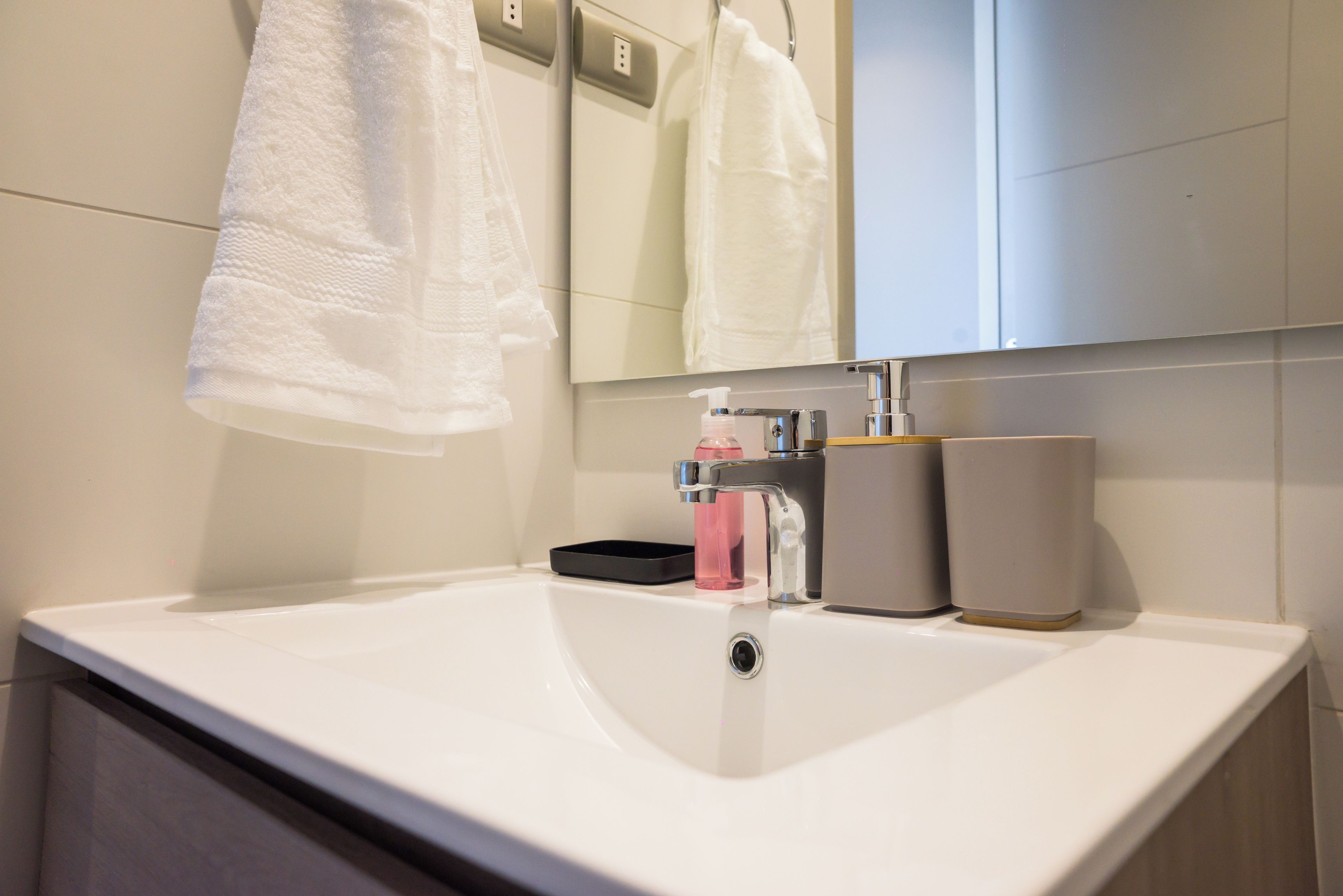 Une salle de bain avec un lavabo blanc, un miroir et une serviette suspendue à un porte-serviettes.