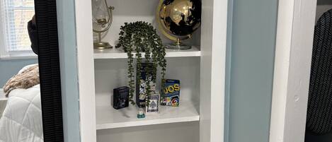 Een witte wandplank met een wereldbol, een plantje en een decoratief object.