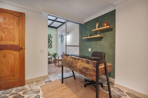 A room with a wooden desk, a chair, a door, and a green wall with shelves. - Peaceful 2-Bedroom Retreat in El Poblado (Medellín)