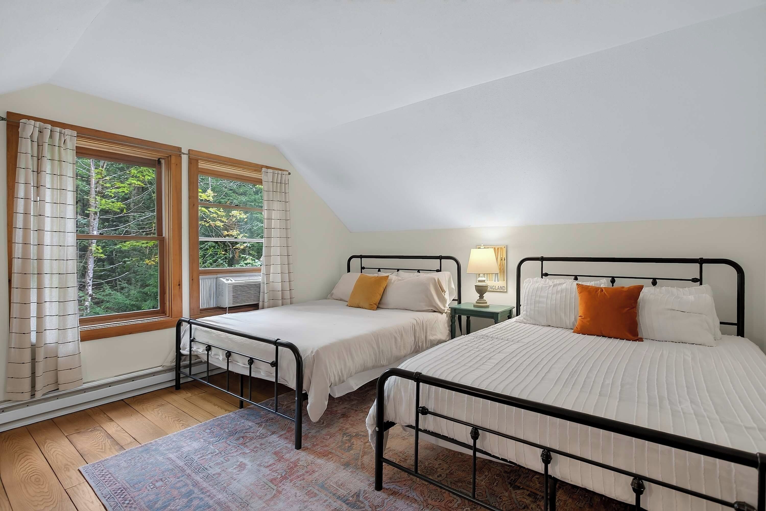 Un dormitorio con dos camas, una ventana con cortinas, un radiador y una alfombra.