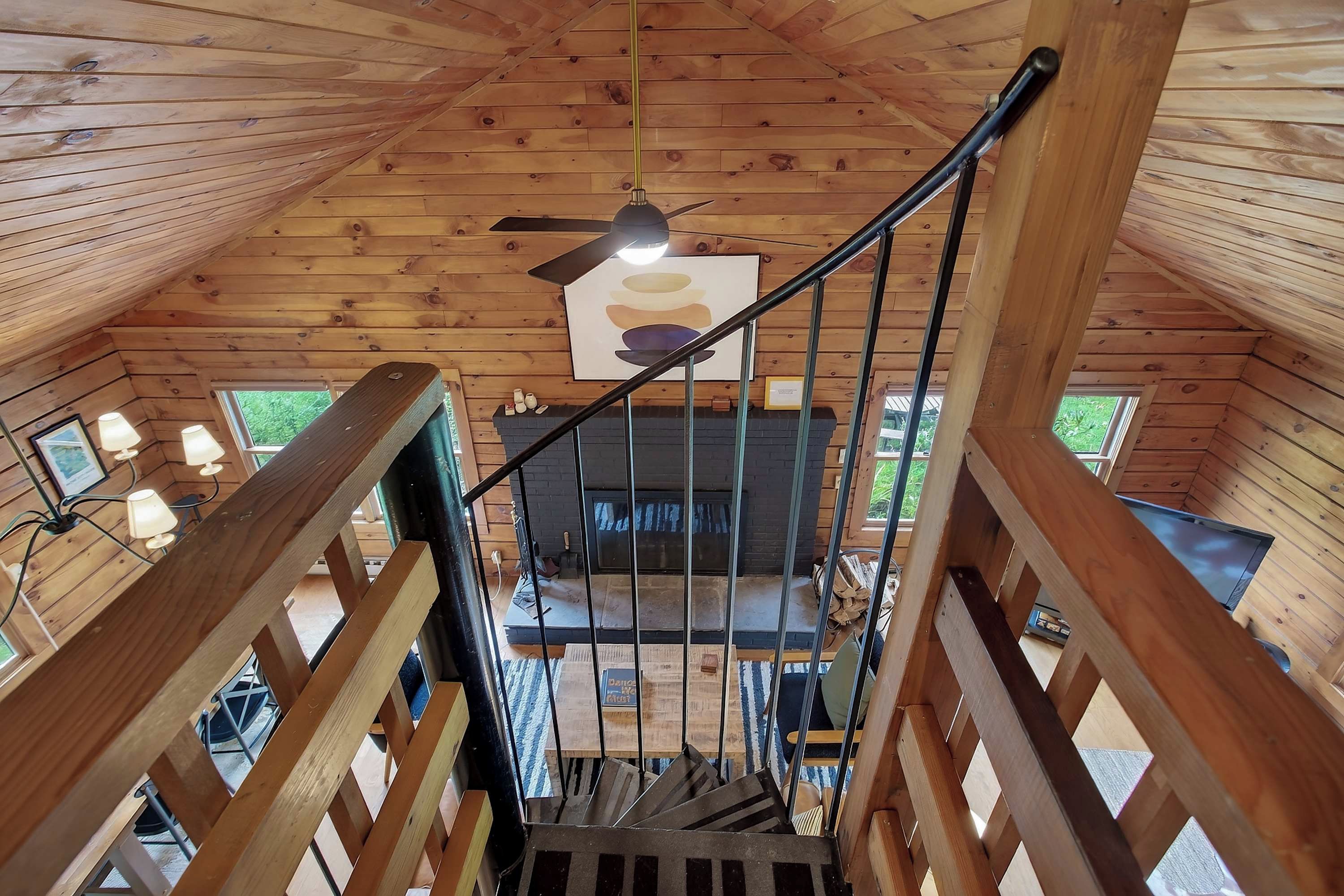 Un interior de madera con una escalera que lleva a una zona con chimenea.