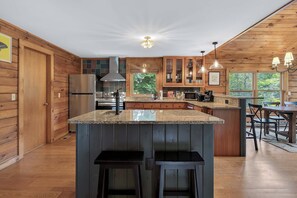 A modern kitchen with wooden cabinetry, a stainless steel refrigerator, and a large island with bar stools.