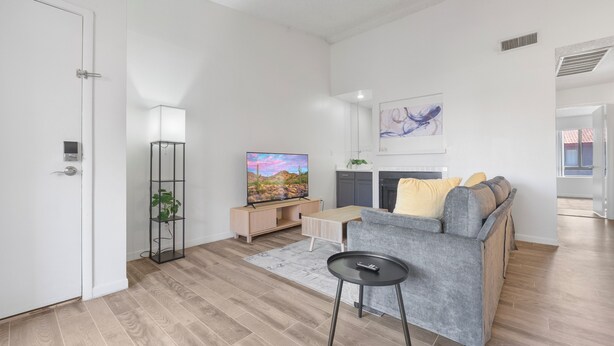Uma sala de estar moderna com sofá, televisão e uma pequena mesa.