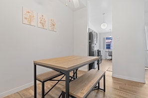 Een moderne keuken met een inbouwoven, een koelkast en een eethoek met een houten tafel en een bank.