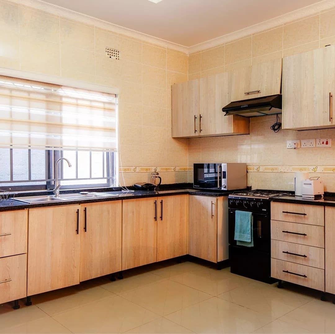 A kitchen with wooden cabinets, a gas stove, a microwave, and a sink.
